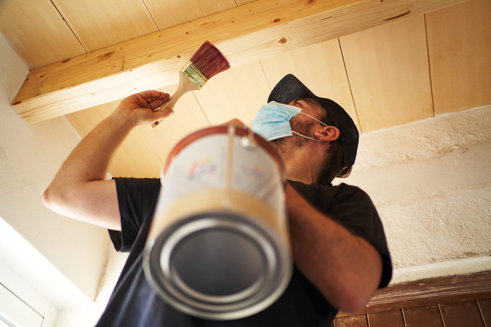 Hispanic man varnishing wooden beam at home