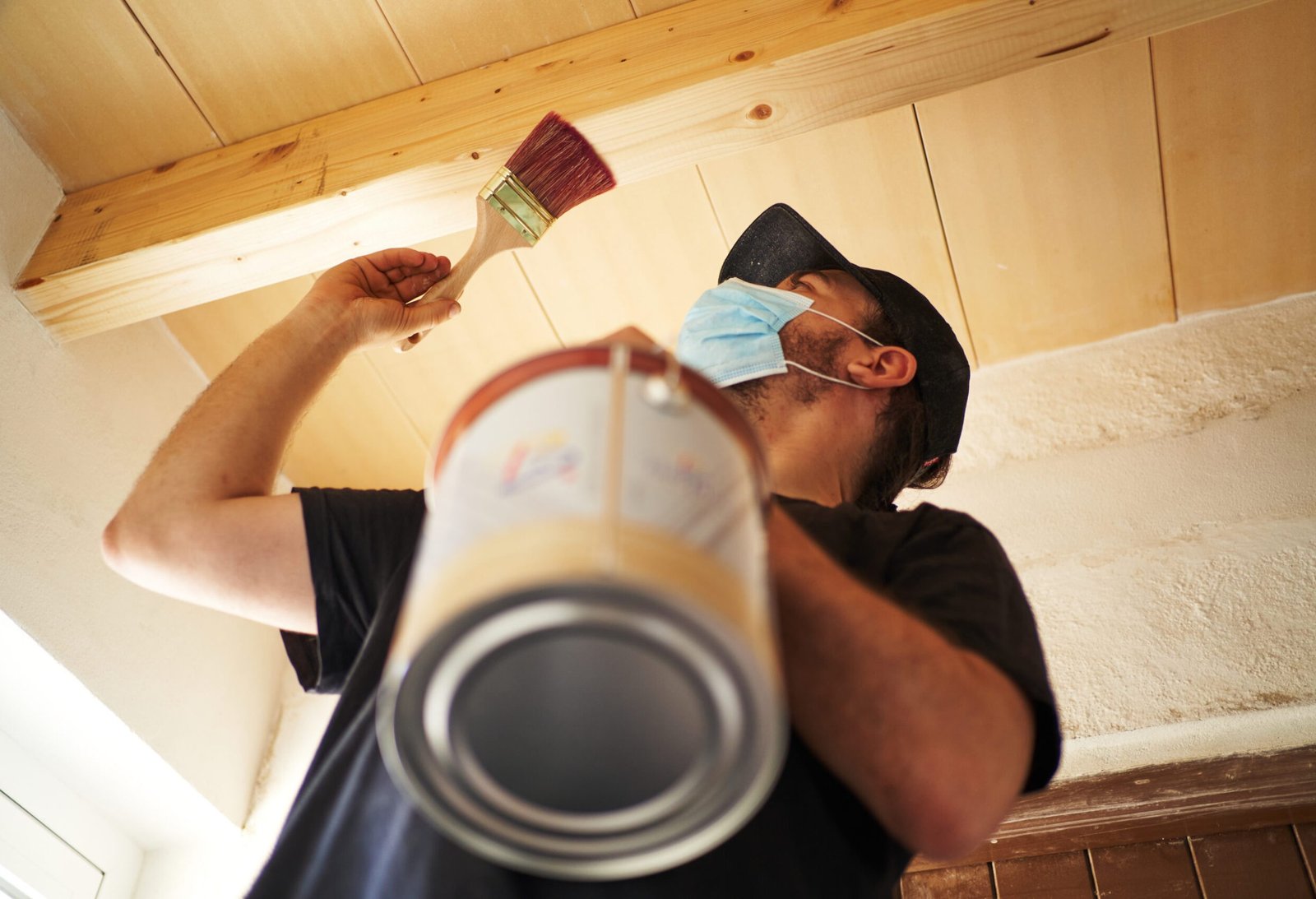 Hispanic man varnishing wooden beam at home